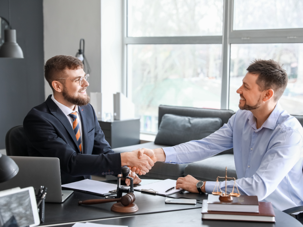 Two men shaking hands over a table.